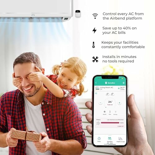 Man holding a gift while a child covers his eyes, with a smartphone showing an air conditioning app interface