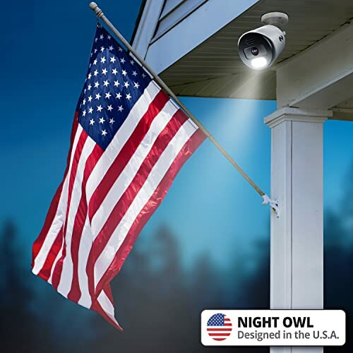 American flag on a pole with a security camera mounted on a house.