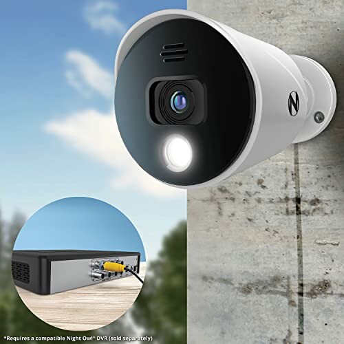 Outdoor security camera mounted on wall with DVR connection.