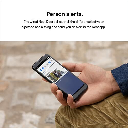 Hand holding smartphone with Nest Doorbell alert displayed.