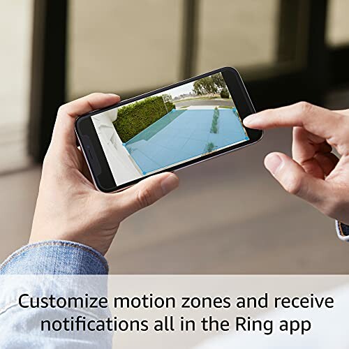 Person using a smartphone to customize motion zones in the Ring app.