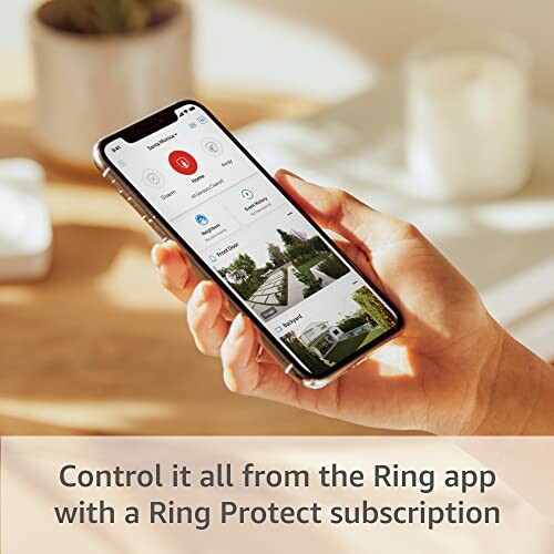 Hand holding smartphone with Ring app interface.