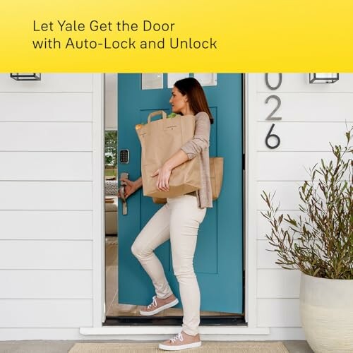 Woman using Yale auto-lock door feature while carrying groceries.